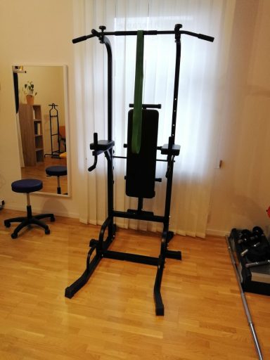 Behandlungsraum Physiotherapie mit einem großen Trainingsgerät und weiteren Utensilien zum Training; daneben ein Spiegel.